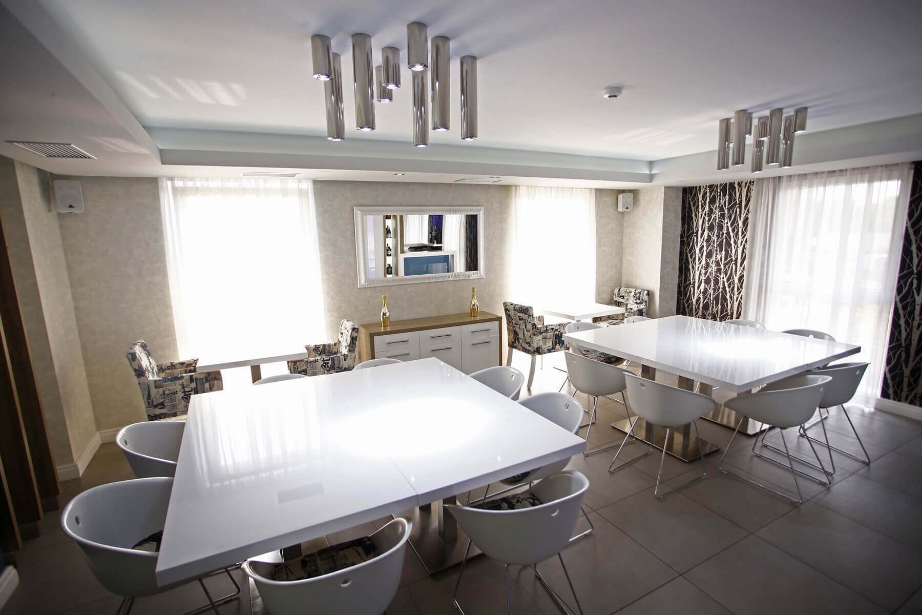 Prostor lounge bara s bijelim stolovima, modernim stolicama i lusterima
