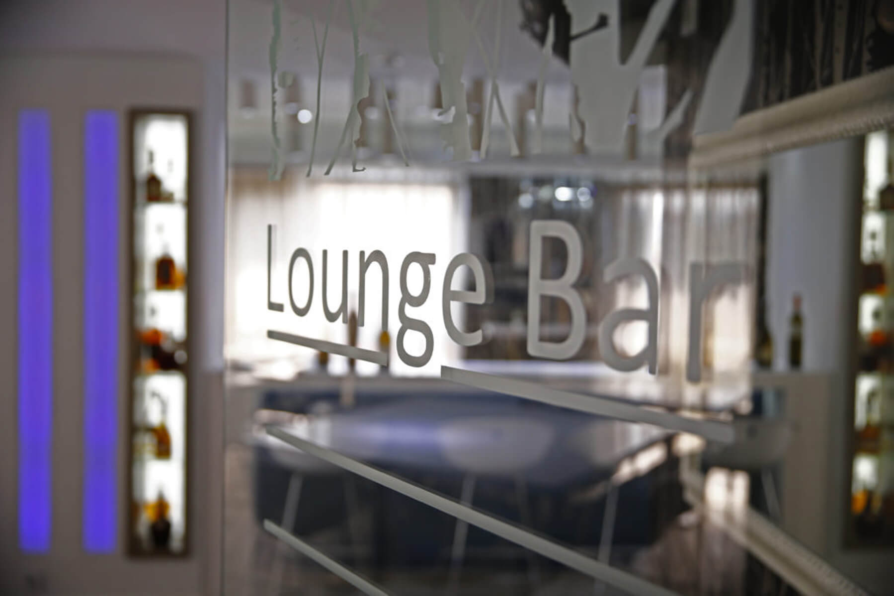 Stakleni natpis Lounge Bar s pogledom na unutrašnjost bara